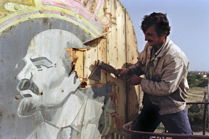 Man removes image of Lenin with axe.