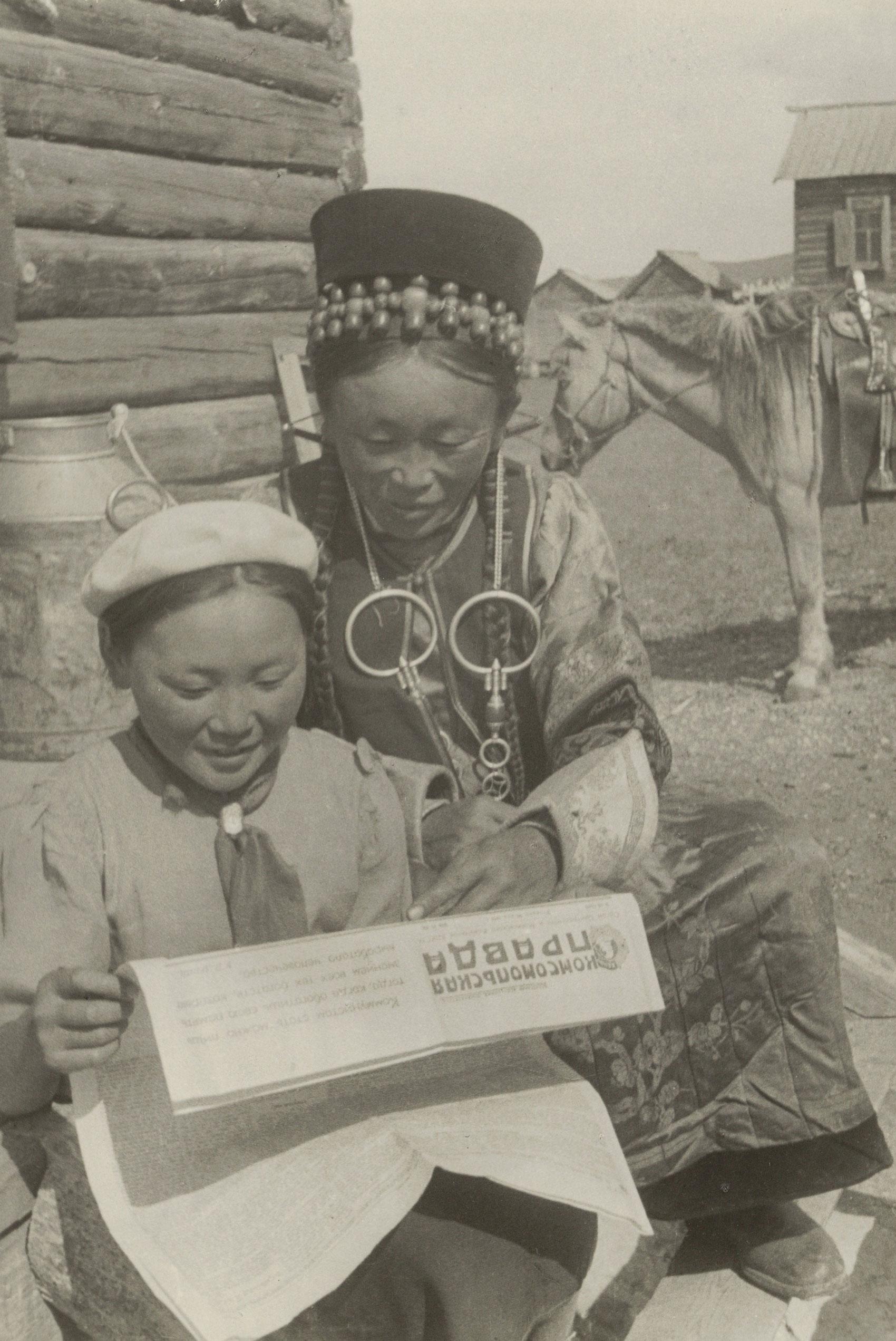 Two Buryat women read the newspaper "Komsomol'skaia pravda."
