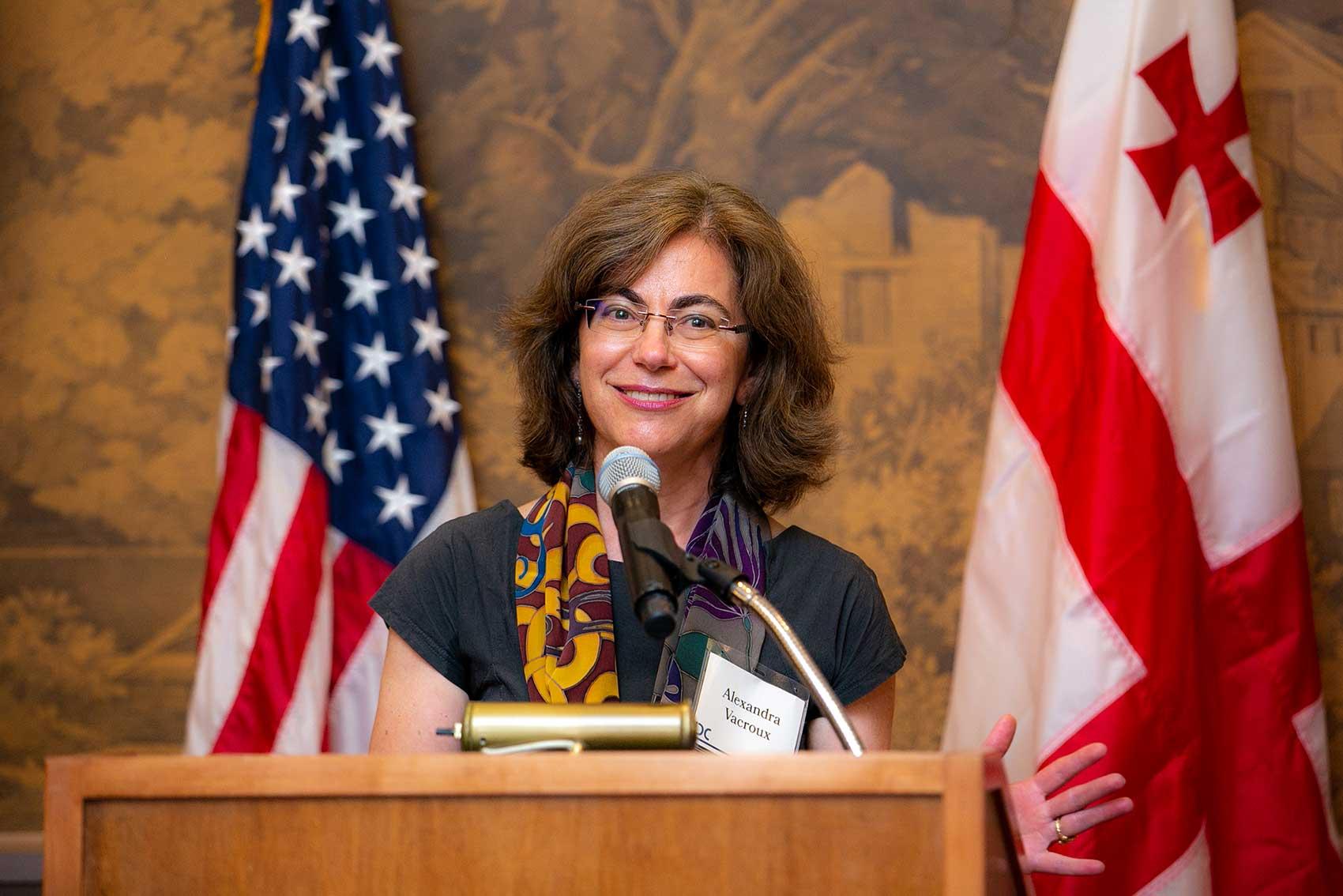 Alexandra Vacroux speaking at podium with U.S. and Georgian flags in background