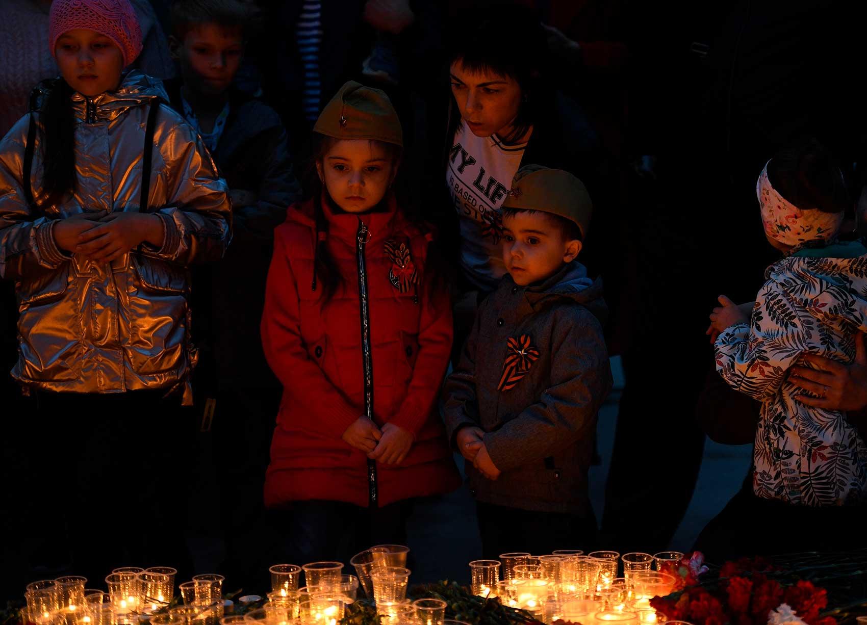 Children stand before candles at World War II remembrance event