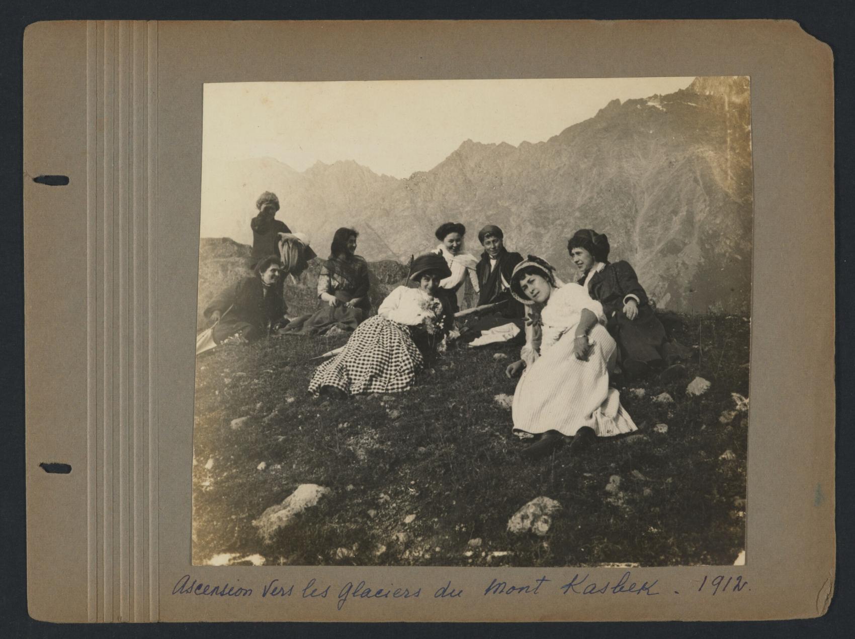 Group of people sitting on a grassy mountain edge