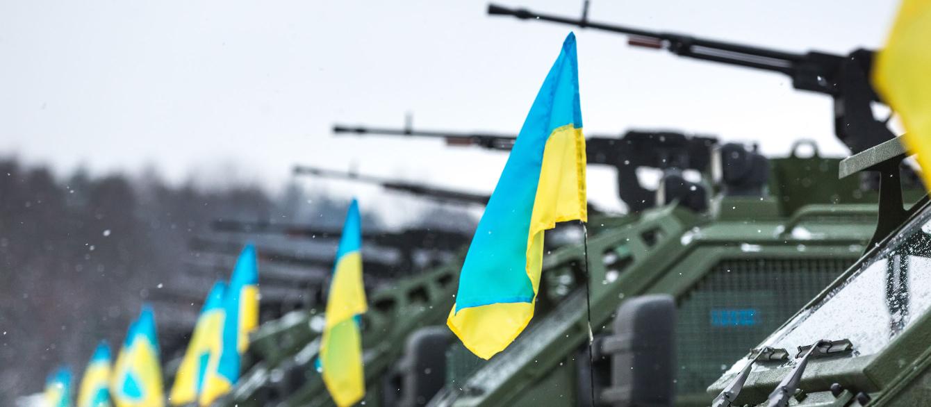 Ukrainian flags against row of tank-mounted guns