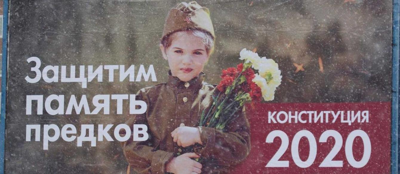 Billboard showing young girl in World War II uniform with bouquet and inscription in Russian, "We will defend the memory of our ancestors. Constitution 2020."