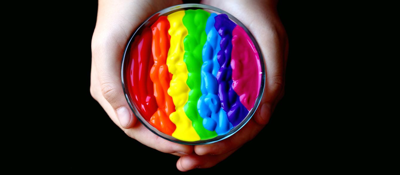 hands holding rainbow paint stripes