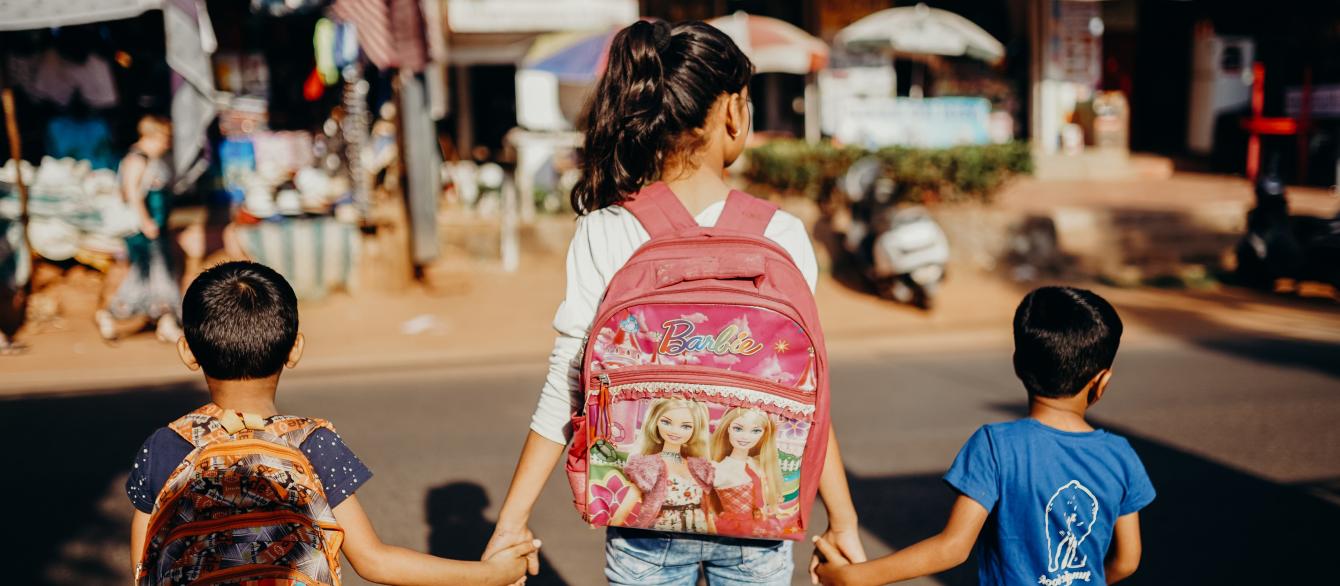 children with backpacks holding hands