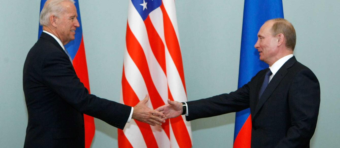 Joe Biden and Vladimir Putin shake hands with US and Russian flags in background