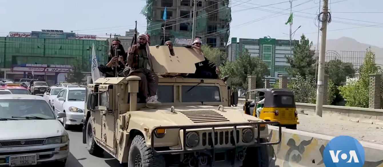 Taliban fighters riding tan humvee on highway