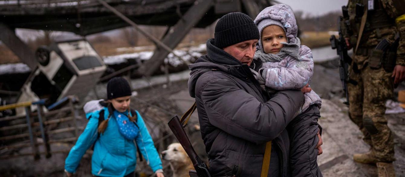 On the outskirts of Kyiv, a local militiaman helps a fleeing family.