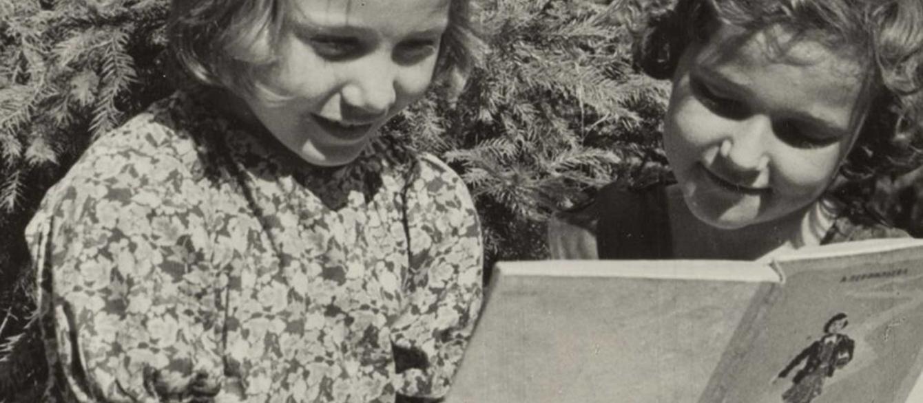 black and white photo of two girls reading a book