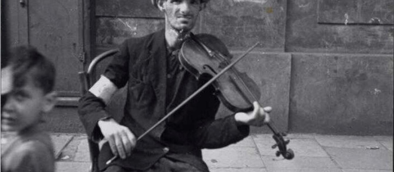  A man on the street plays the violin in the hope of receiving food or money