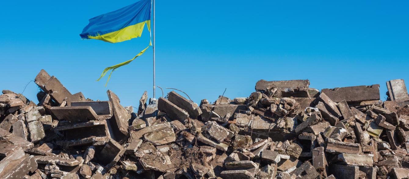  Destroyed Ukrainian building and damaged flag in the wind.
