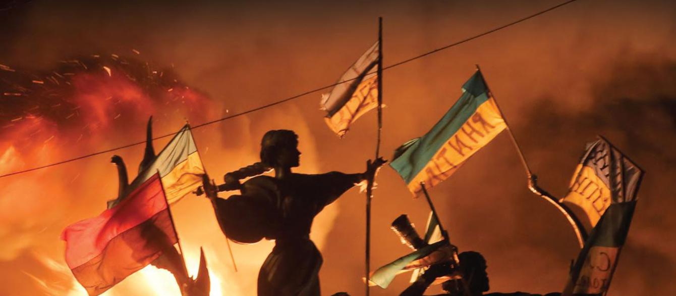 statues with Ukrainian flags in the backdrop of the fire at night