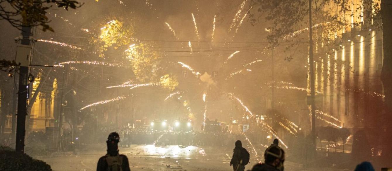 Fireworks burst over riot police gathered on Rustaveli Avenue in the early hours of 4 December