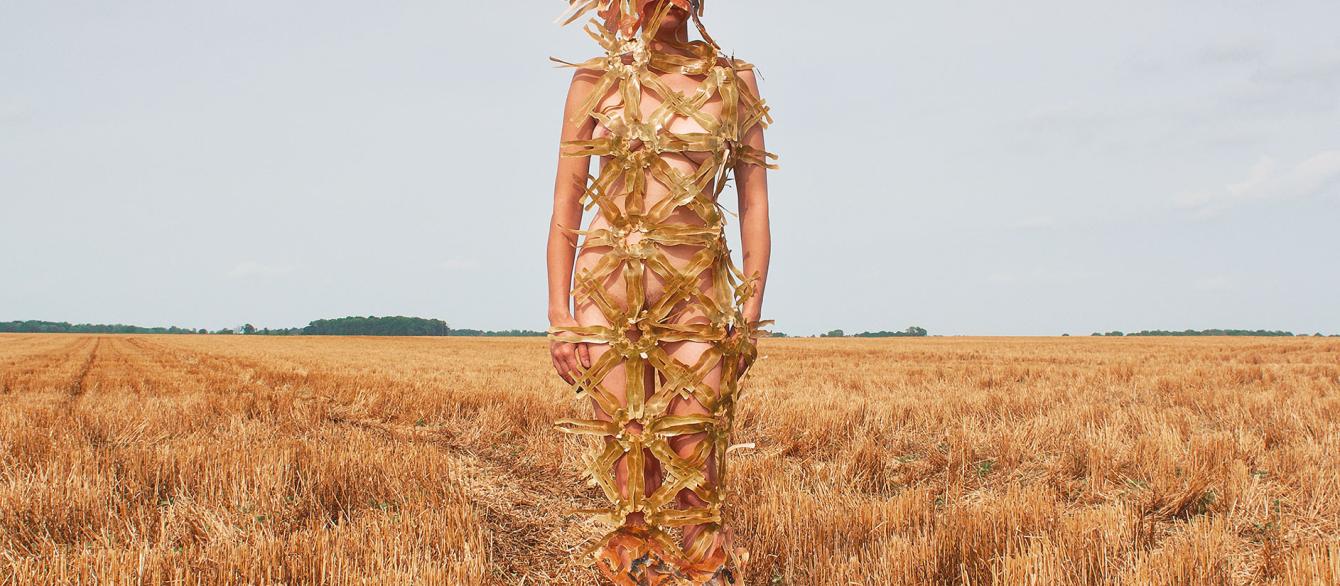 a woman dressed in paper textiles in the field of hay