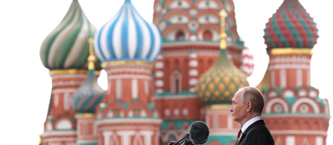 Putin at podium and microphone against onion dome background