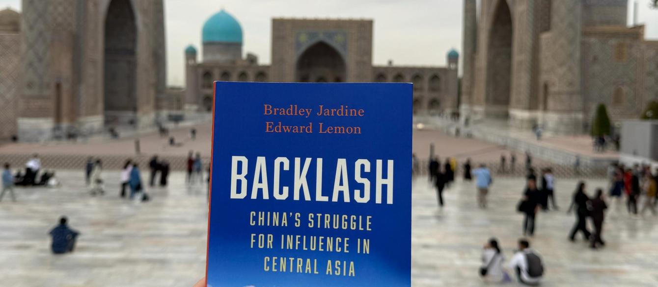 Backlash book held in hands, in the backdrop plaza in Central Asia