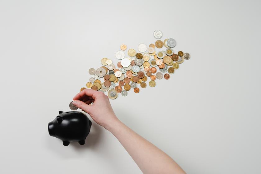 hands putting international coins into piggy bank