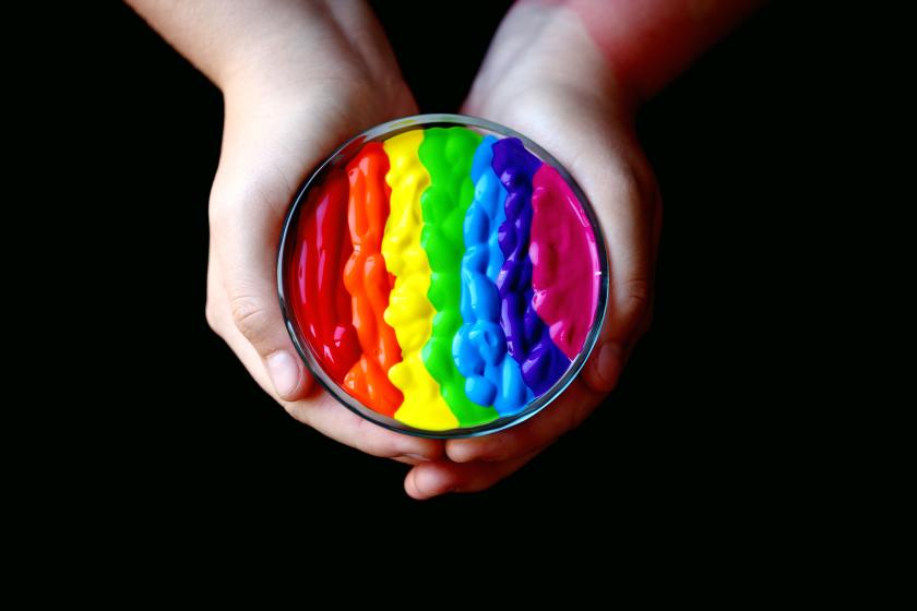 hands holding rainbow paint stripes