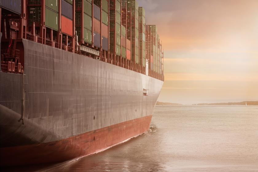 shipping container carrying cargo through calm sunlit water