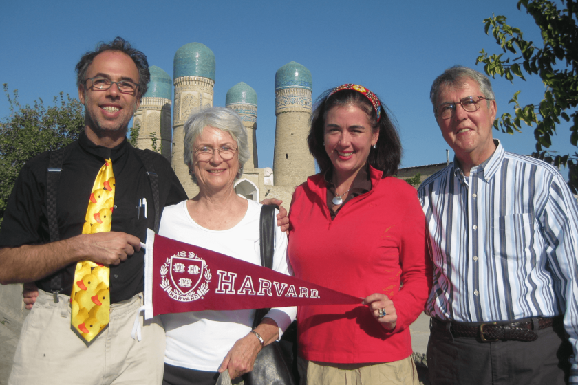 Ambassador Simons with three others in front of an Uzbek historical site holding a Harvard flag