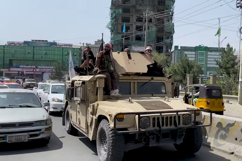 Taliban fighters riding tan humvee on highway
