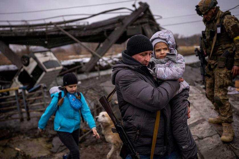 On the outskirts of Kyiv, a local militiaman helps a fleeing family.