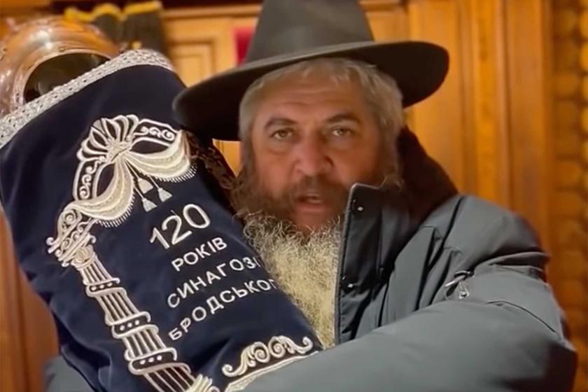 Rabbi Moshe Reuven Asman holding Torah scroll with Ukrainian writing on cover