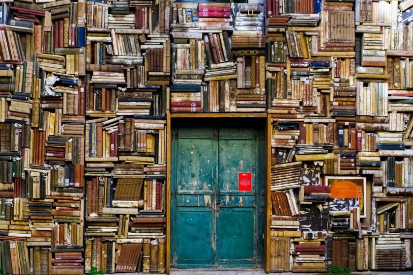 blue wooden door surrounded by book covered wall
