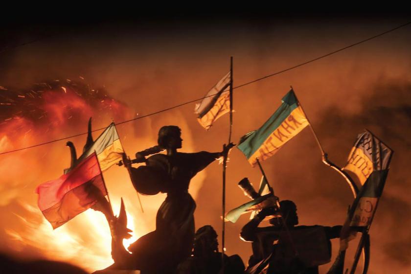 statues with Ukrainian flags in the backdrop of the fire at night