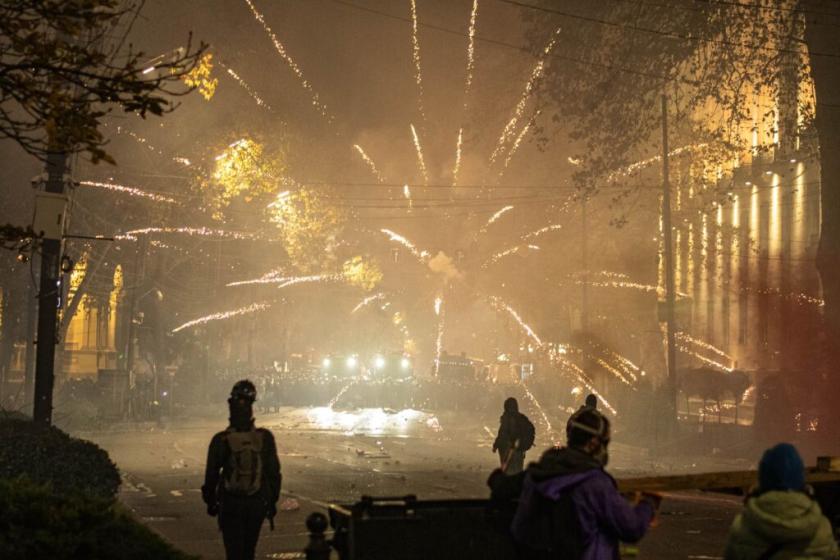 Fireworks burst over riot police gathered on Rustaveli Avenue in the early hours of 4 December