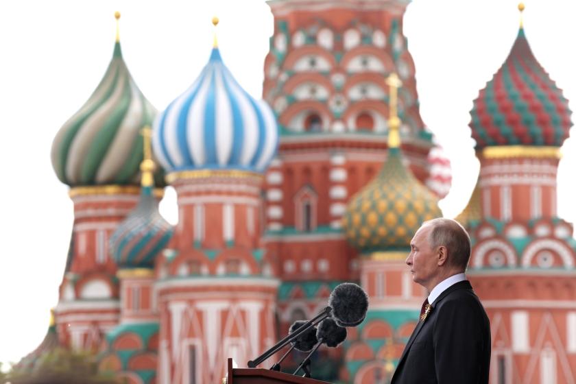 Putin at podium and microphone against onion dome background