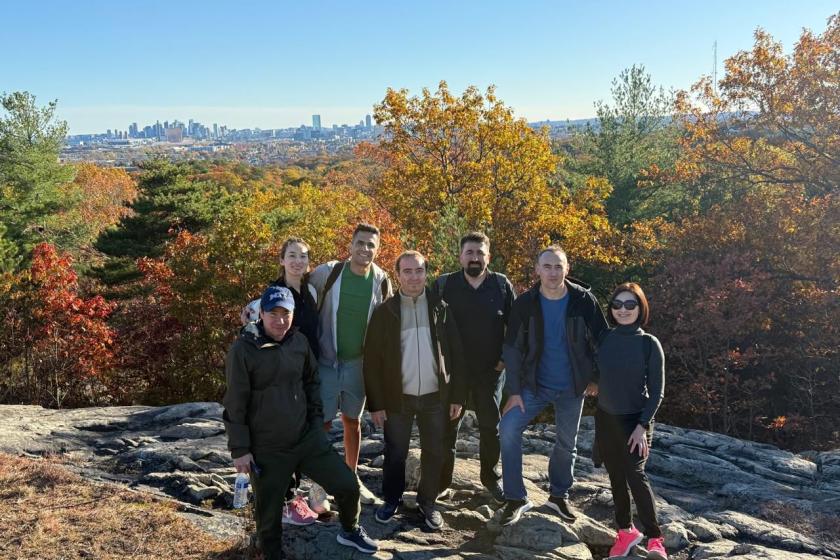 group of hikers with fall foliage and Boston skyline in background