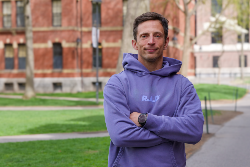 Man in a purple sweatshirt standing with his arms crossed