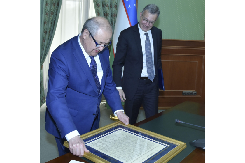Two men leaning over a framed document 