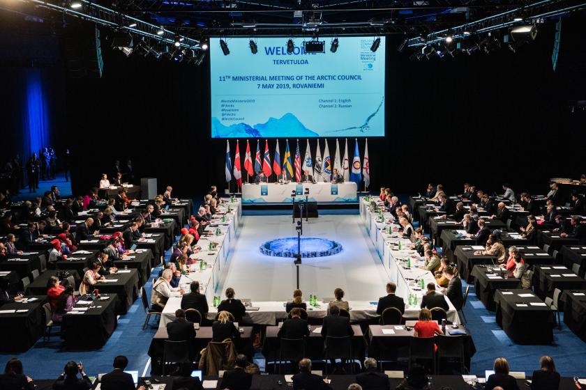 large room hosting Arctic Council meeting with screen for slides
