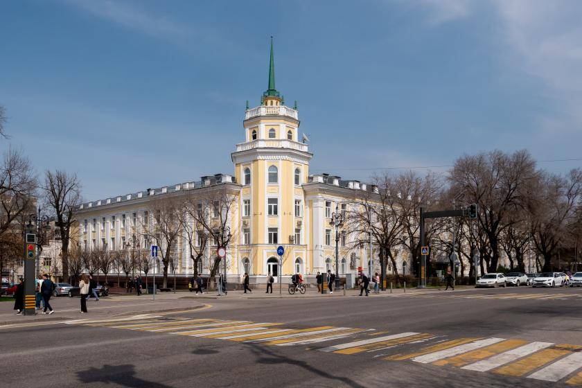 neoclassical pale yellow building flanked by bare trees with blue sky above